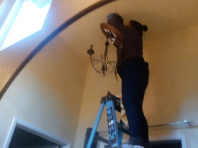 Electrician installing a chandelier in a Lima residence